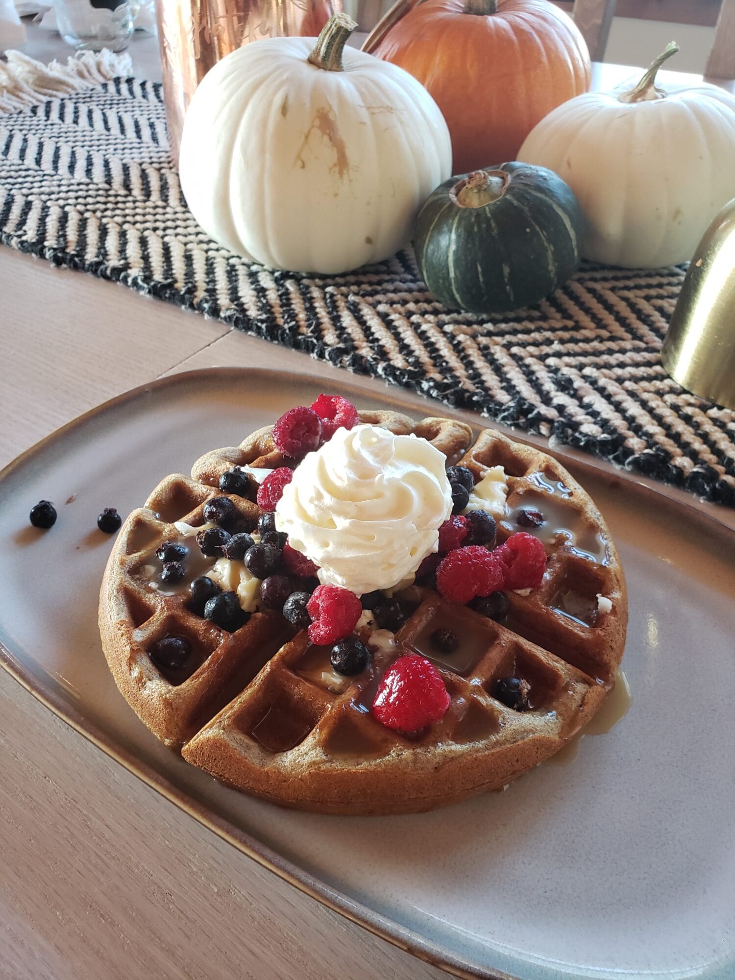 A waffle with whipped cream and berries on top.