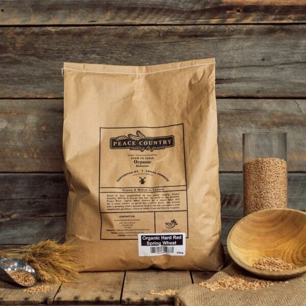 A bag of flour next to a wooden bowl and glass.